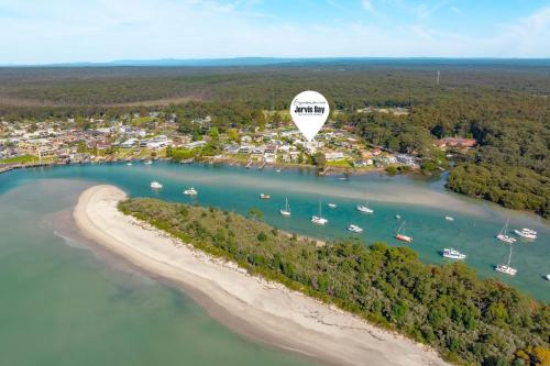 an hot air balloon flying over a beach and boats at Pier 8 by Experience Jervis Bay in Huskisson