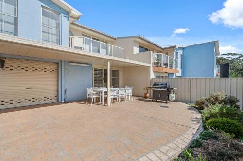 a house with a patio with a table and chairs at Pier 8 by Experience Jervis Bay in Huskisson