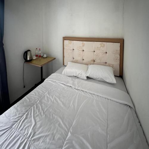 a bed in a small room with a table at AN Homestay Syariah Mitra RedDoorz Wonosobo in Wonosobo