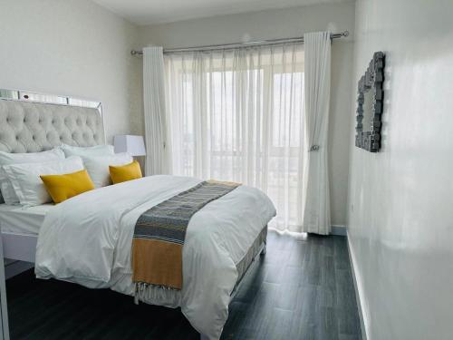 Un dormitorio con una cama con almohadas amarillas y una ventana. en casamia luxury apartments, en Nairobi