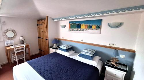 a bedroom with a blue and white bed and a desk at Hôtel Les Embruns Sables d'Olonne in Les Sables-dʼOlonne