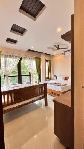 a bedroom with two beds and a large window at Arjun Homestay in Hampi