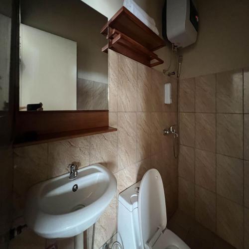 a bathroom with a sink and a toilet and a mirror at AN Homestay Syariah Mitra RedDoorz Wonosobo in Wonosobo