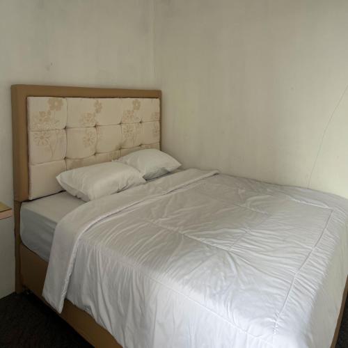 a bed with white sheets and pillows in a room at AN Homestay Syariah Mitra RedDoorz Wonosobo in Wonosobo