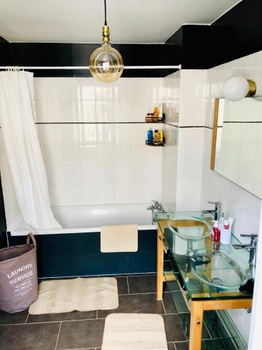 La salle de bains est pourvue d'une table en verre et d'une baignoire. dans l'établissement Grande maison pêcheur. Centre ville Trouville, à Trouville-sur-Mer