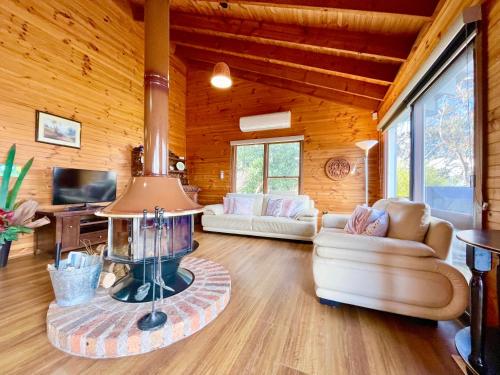 a living room with a fireplace in a log cabin at Treetops Retreat Katoomba in Katoomba