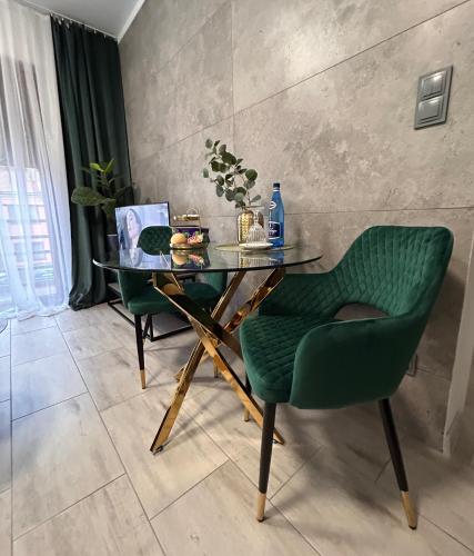a table and two green chairs in a room at Przy Złotych Piaskach 1 in Sława
