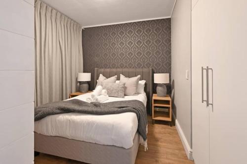 a bedroom with a bed and two tables with lamps at Bella - Stylish 1-Bed Apt in trendy De Waterkant with Balcony in Cape Town