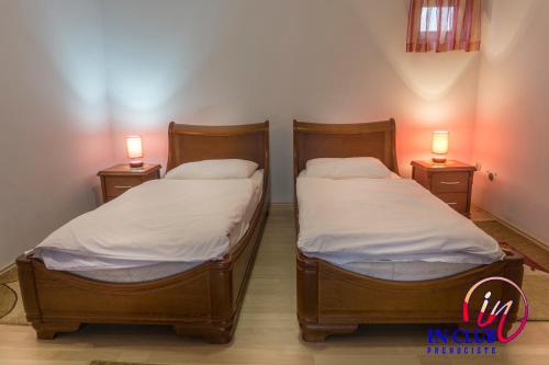 two beds in a room with two lamps on the sides at Apartment and Rooms In Club in Inđija
