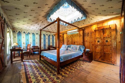 a bedroom with a canopy bed and a table at Maa Ashapura Resort in Sawāi Mādhopur