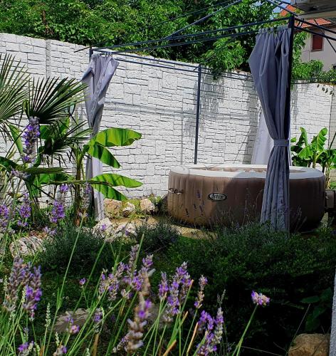 a garden with a bath tub in the grass at Stone Spa Apartman 2 in Sremčica