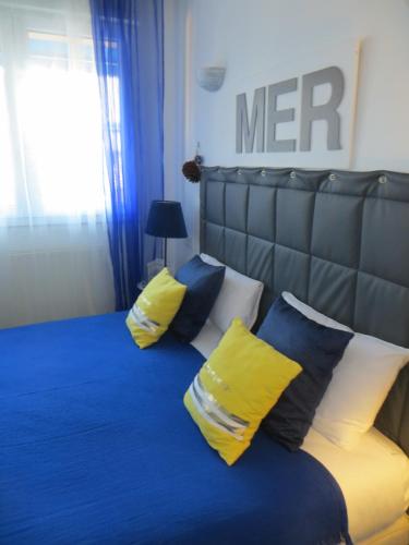 a bedroom with a bed with yellow and blue pillows at Hôtel Les Embruns Sables d'Olonne in Les Sables-dʼOlonne