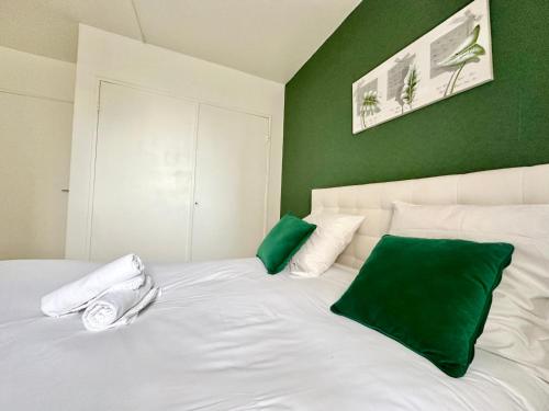 - une chambre avec un lit blanc aux murs verts dans l'établissement Le Montjovis, spacieux et lumineux avec garage, à Limoges