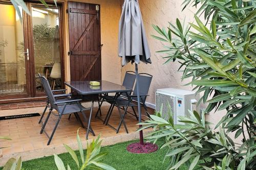 un patio avec une table, des chaises et un parasol dans l'établissement Le Sérénité -clim-wifi-proche centre ville-plages, à Hyères