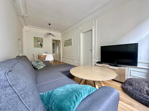 un salon avec un canapé bleu et une table dans l'établissement L'Haussmannien, splendide et lumineux, à Limoges