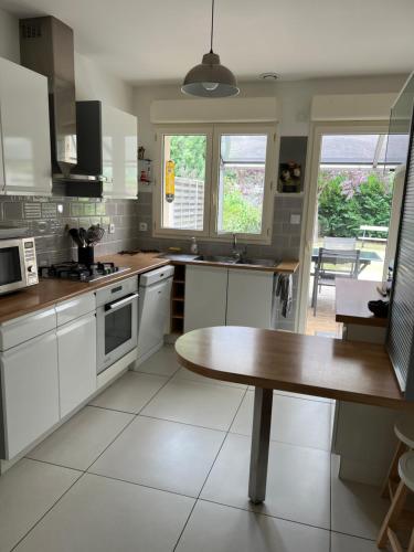 une cuisine avec des armoires blanches et une table en bois dans l'établissement La douceur Angevine !, à Les Ponts-de-Cé