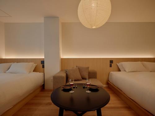 a room with two beds and a table with glasses of wine at THE SENSE HOTEL TOKYO in Tokyo