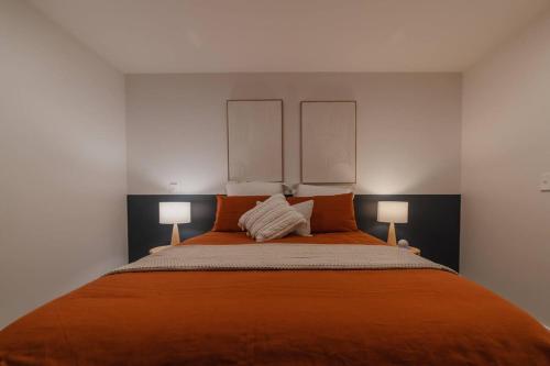 a bedroom with a large orange bed with two lamps at Luxury Central City Getaway in Christchurch