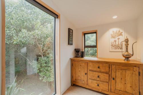 a room with a large window and a wooden dresser at Ocean Views at Rapanui Lodge- 4BR Gem with Parking in Christchurch