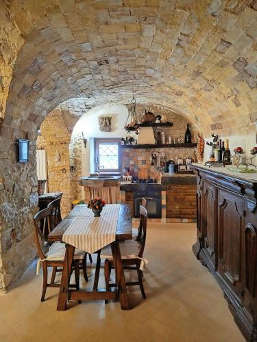 a kitchen with a table and chairs and a stone wall at Domus Pia in Rocca Pia
