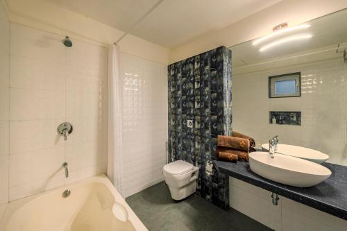 a bathroom with a tub and a sink and a toilet at SaffronStays Horizon 360, A Short Walk From Venna Lake and Mahabaleshwar Market in Mahabaleshwar