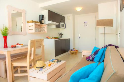 un salon avec un canapé et une table et une cuisine dans l'établissement Résidence Goélia Les Jardins de l'Oyat, à Mimizan-Plage