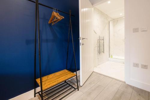 a bathroom with blue walls and a shower with a bench at Madison 2 Bedroom, 2 Bath Apartment in Hemel Hempstead