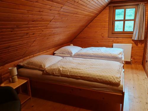 two beds in a wooden room with a attic at Chata KORSO v súkromí so záhradou 1200m2 in Terchová