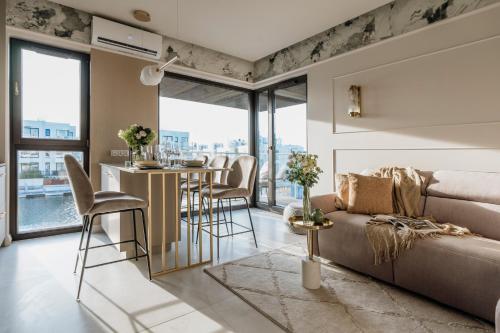 a living room with a couch and a table with chairs at Sol Marina Resort Wyspa Sobieszewska II - LoftAffair Collection in Wiślinka