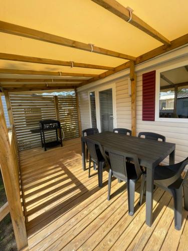 un patio avec une table et des chaises sur une terrasse dans l'établissement Mobilhome au CAP FERRET - Camping 4 étoiles, à Lège-Cap-Ferret