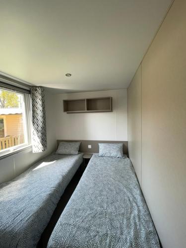 deux lits dans une petite pièce avec une fenêtre dans l'établissement Mobilhome au CAP FERRET - Camping 4 étoiles, à Lège-Cap-Ferret