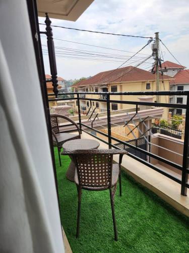 a balcony with two chairs and a table on the grass at Abba Homes in Bulambiro