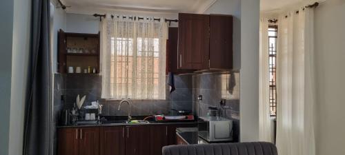 a kitchen with brown cabinets and a sink and a window at Abba Homes in Bulambiro