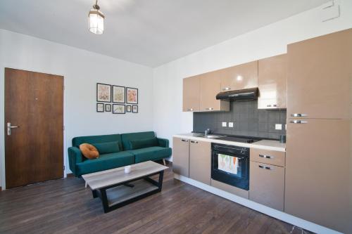 a living room with a green couch in a kitchen at Le Petit St André - Appt pour 4 in Saint-André-les-Vergers