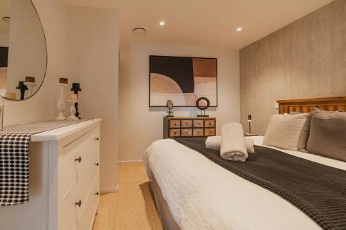 a bedroom with a large bed and a mirror at Penthouse Perfection - 2BR Elegance on Worcester St in Christchurch
