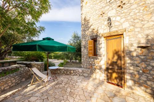 a green umbrella sitting next to a table and a chair at Stone Farmhouse in Groves - Sea & Mountain Views in Kalamaki Messinia