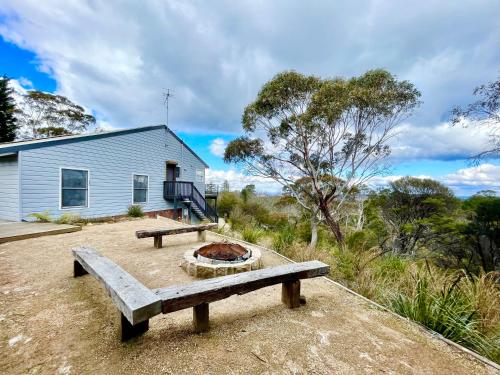a building with a picnic table and a fire pit at Treetops Retreat Katoomba in Katoomba