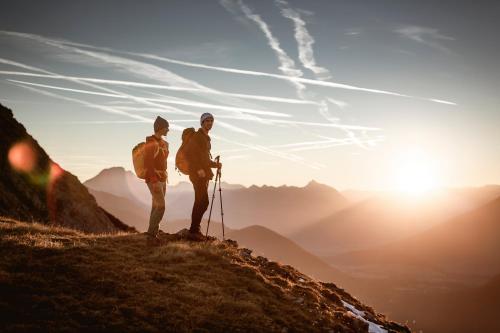 two people standing on top of a mountain looking at the sunset at Apartments Gabl in Schönwies