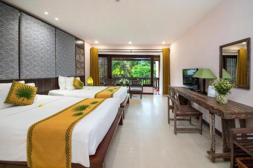 a hotel room with two beds and a television at Palm Garden Beach Resort & Spa in Hoi An