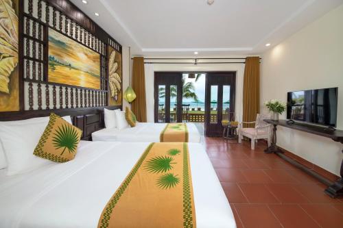 a hotel room with two beds and a television at Palm Garden Beach Resort & Spa in Hoi An