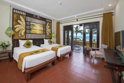 a hotel room with two beds and a balcony at Palm Garden Beach Resort & Spa in Hoi An