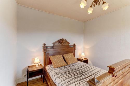 a bedroom with a wooden bed with two lamps at Les Bois Noirs - appt vue montagne in Arconsat