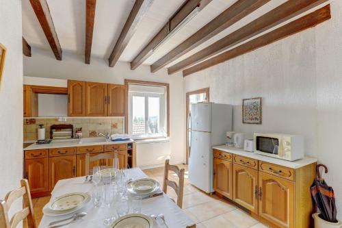 une cuisine avec une table et un réfrigérateur blanc dans l'établissement Les Bois Noirs - appt vue montagne, à Arconsat