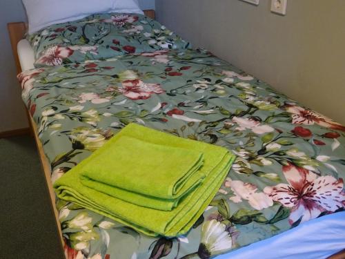 a bed with a green towel on top of it at Pension und Gästehaus Paffrath in Großbrembach