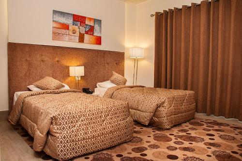 2 Betten in einem Hotelzimmer mit Vorhängen in der Unterkunft Marble Tower in Beirut