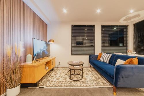 a living room with a blue couch and a tv at Fitzgerald Focus - Your 1BR Urban Oasis in Christchurch