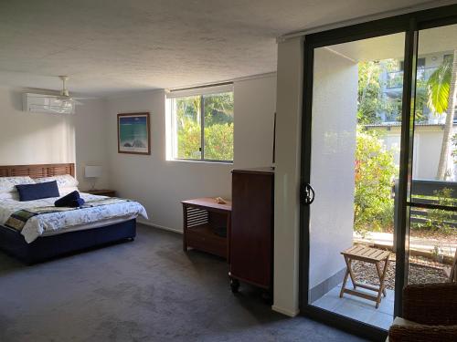 a bedroom with a bed and a sliding glass door at Emohruo Rainbow Shores - 3 Br Resort Apartment in Rainbow Beach