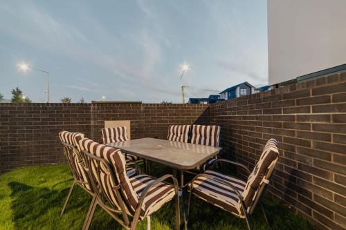 a table with four chairs and a brick wall at Fitzgerald Focus - Your 1BR Urban Oasis in Christchurch