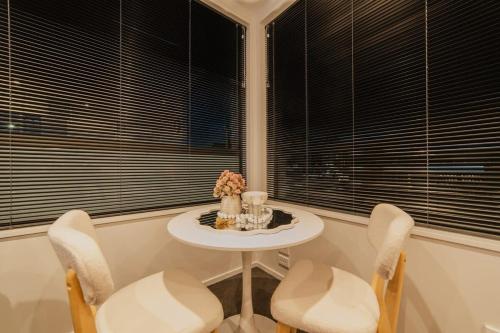 a table and chairs in a room with windows at Fitzgerald Focus - Your 1BR Urban Oasis in Christchurch