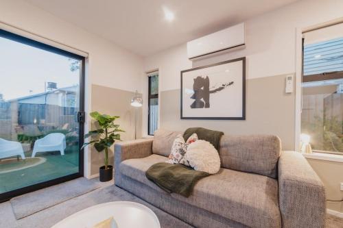 クライストチャーチにあるMisty Meadows Manor - Your Urban Oasisのソファと大きな窓のあるリビングルーム